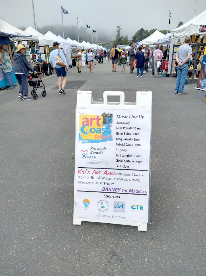 Signage, booths, and attendees at Art on the Coast Festival in Brookings, Oregon