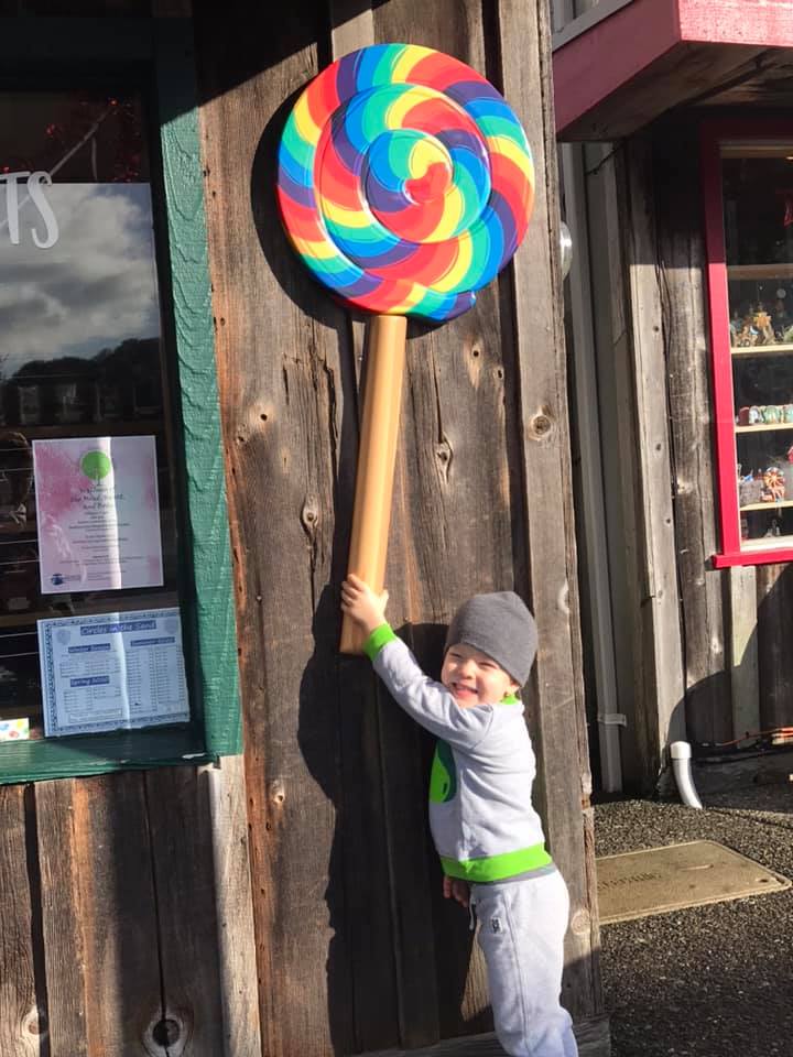 Child with large outdoor lollipop at Bandon Sweets and Treats in Bandon, Oregon
