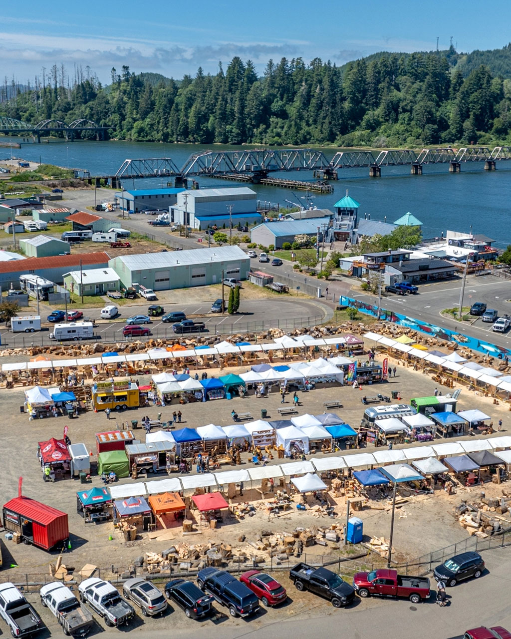 Aerial view of outdoor event with numerous vendor booths under tents.