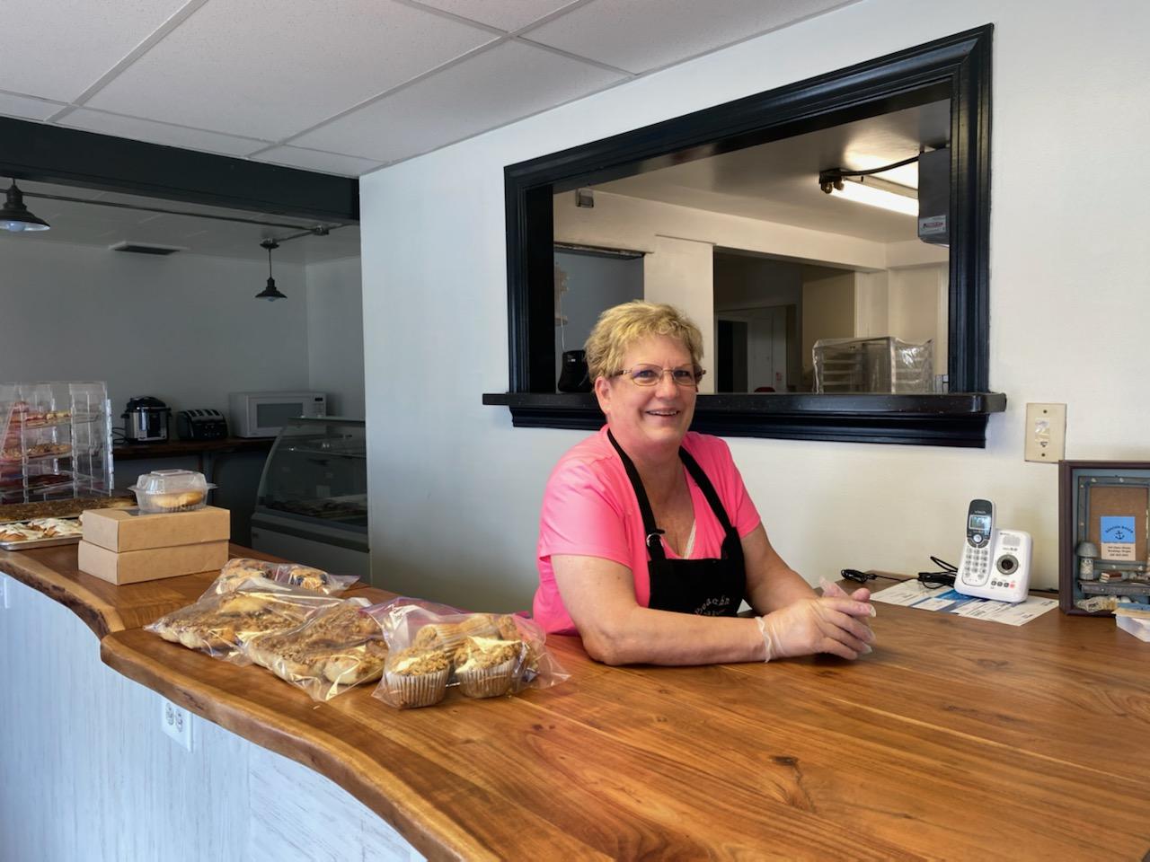 person smiling at camera from behind a counter at a business