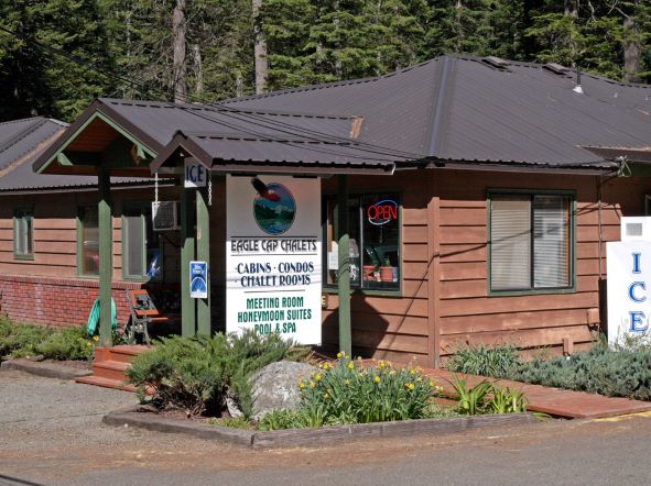 exterior of a one-story building with adjacent signage that reads: Eagle Cap Chalets - Cabins/Condos/Chalet Rooms