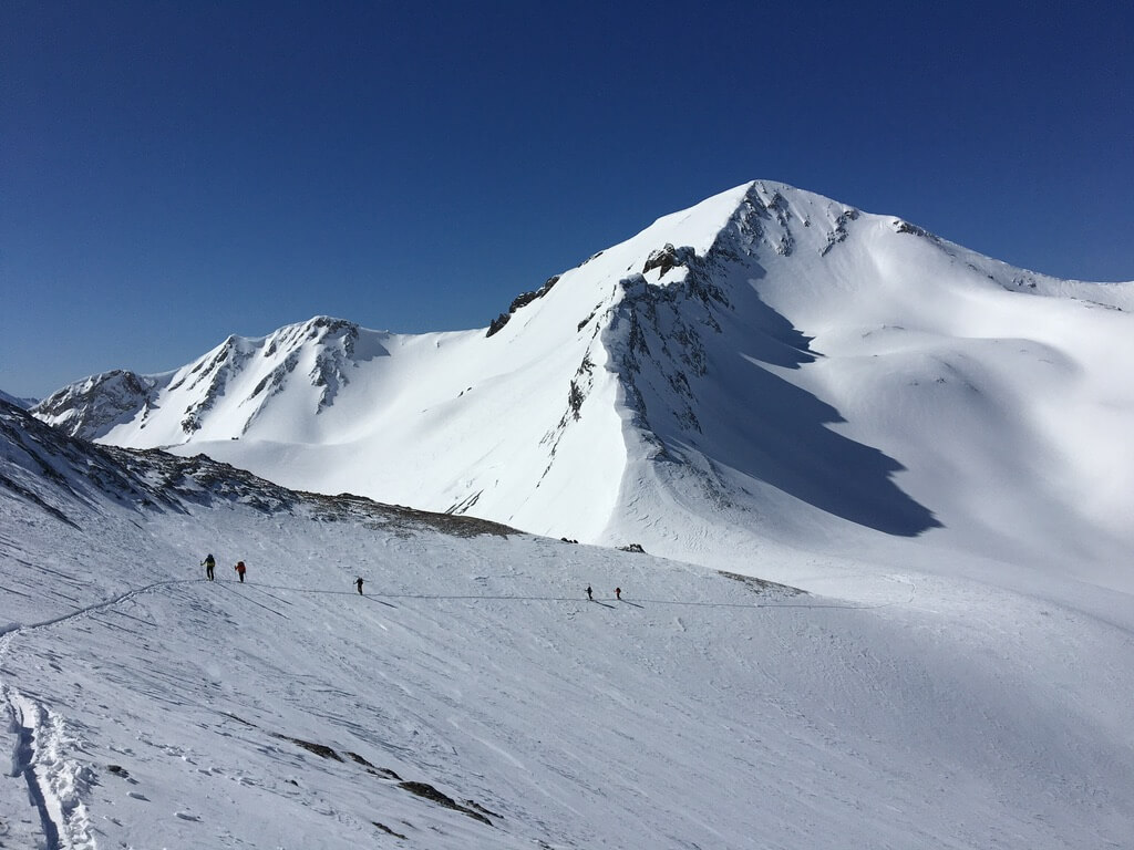 wide angle of Cusick Mountain with backcountry skiers in the distance hiking the ridgeline