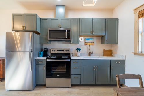 kitchenette for the Bon Temps Suites featuring a teal kitchen with stainless steel applicances