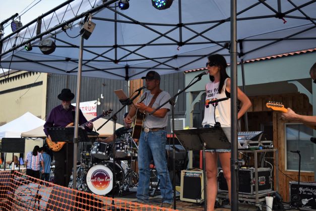 a multi-piece band on stage under a white tent