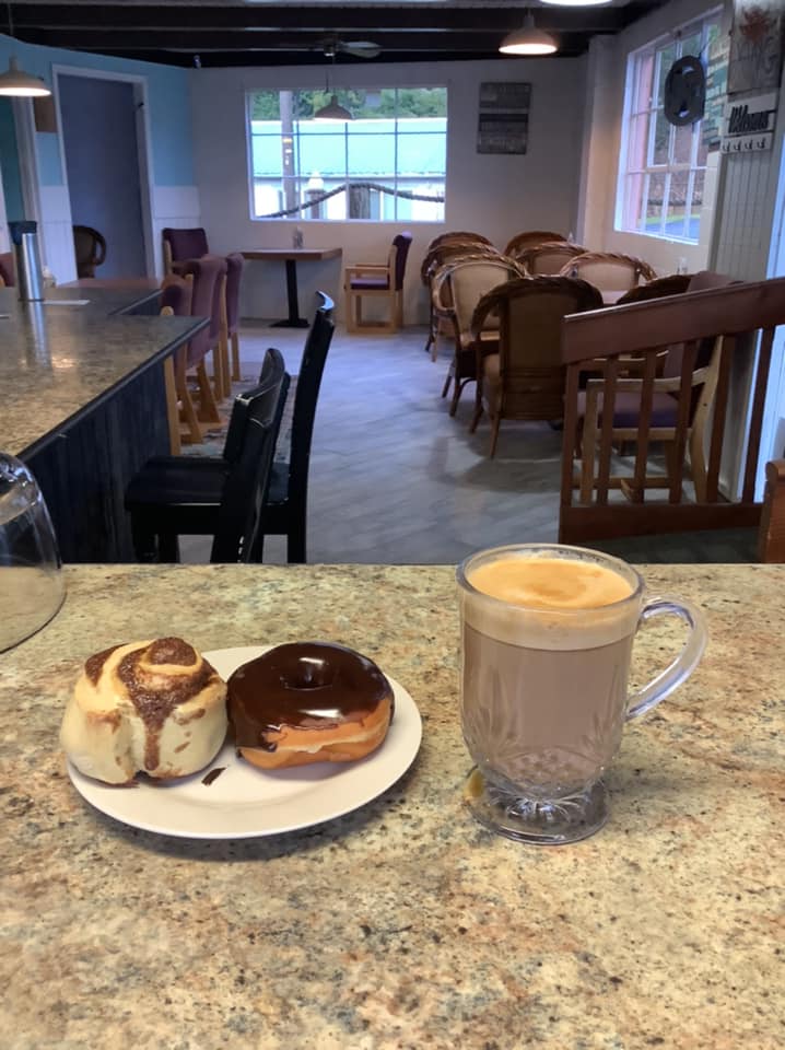 cinnamon roll and fancy coffee on countertop with view of dining room