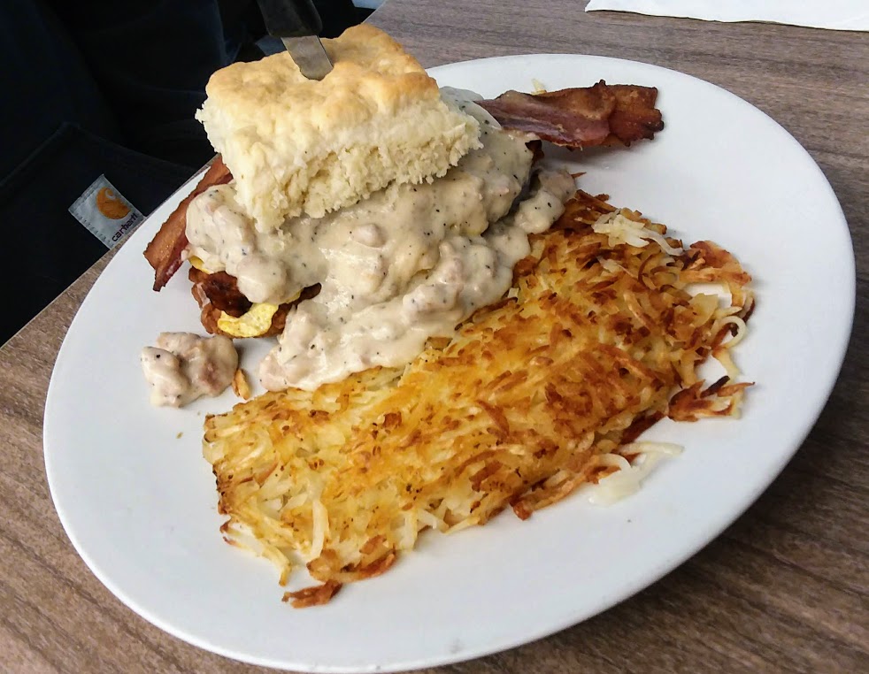 freshly baked biscuit topped with scrambled eggs, peppered bacon and country gravy