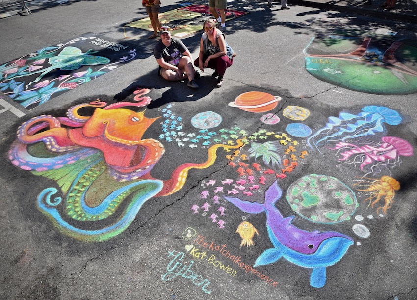 Artists posing next to their chalk work