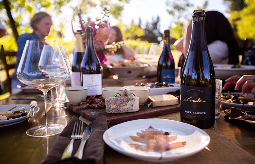 An outdoor table is set with cheese and Lundeen wine.