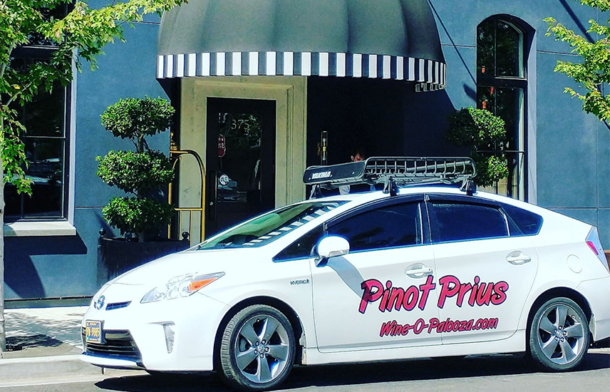 A white Prius is parked in front of a hotel.