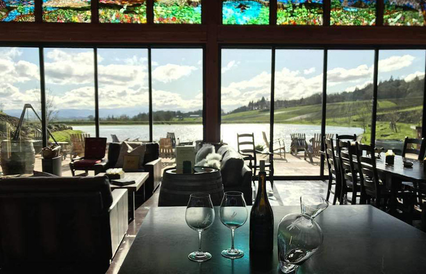 A tasting room with large windows overlooking a lake.