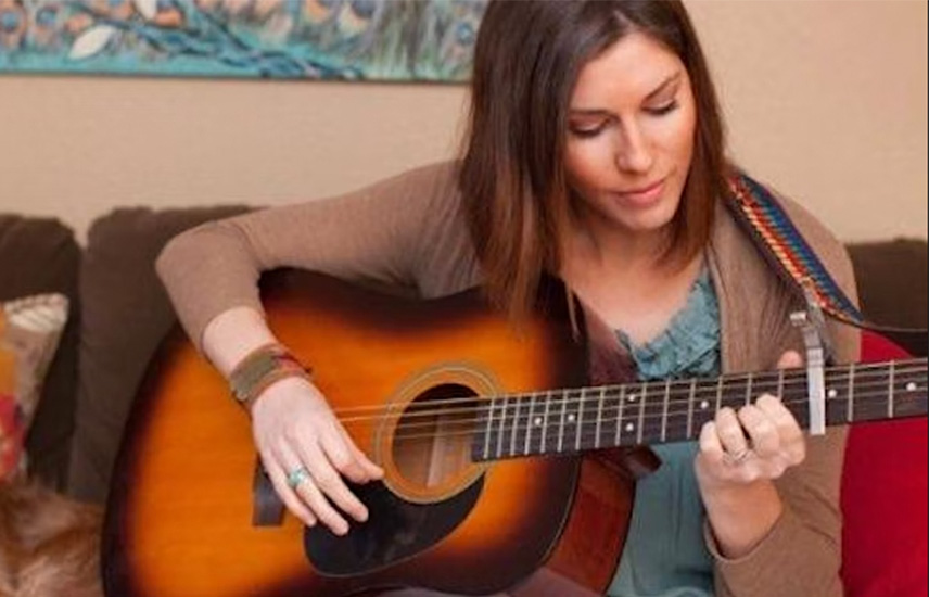 A woman plays an acoustic guitar.