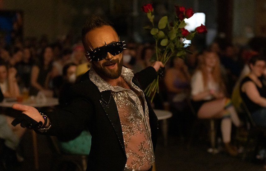 A drag king performs a lip sync in front of a crowd.