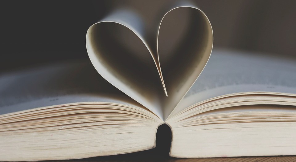 An open book with two pages curled into a heart.