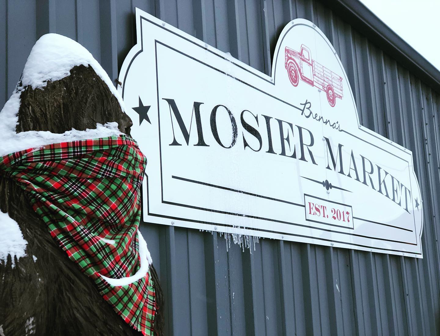 Bigfoot statue covered in snow next to Mosier Market sign