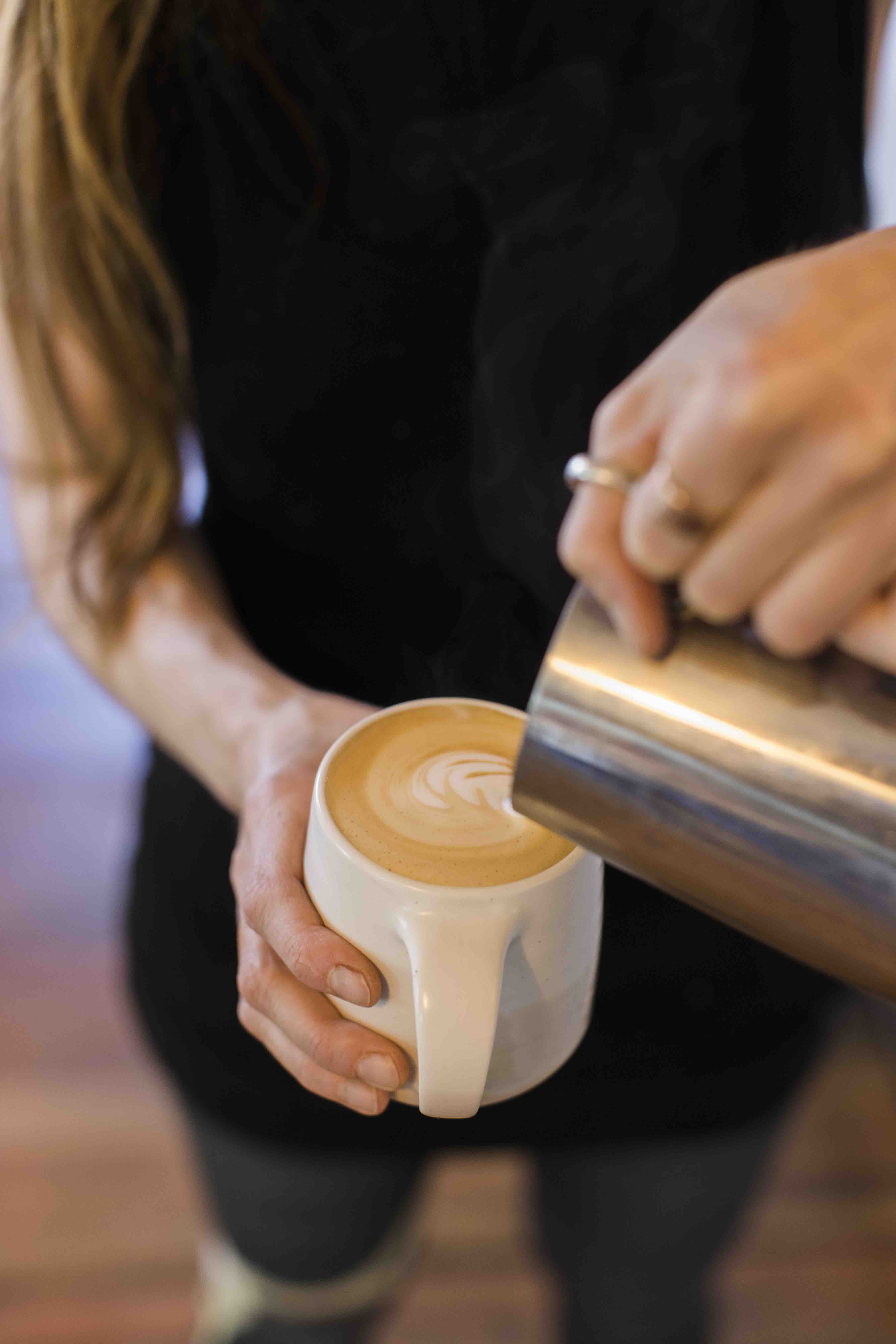 Latte in hand of barista with foam art
