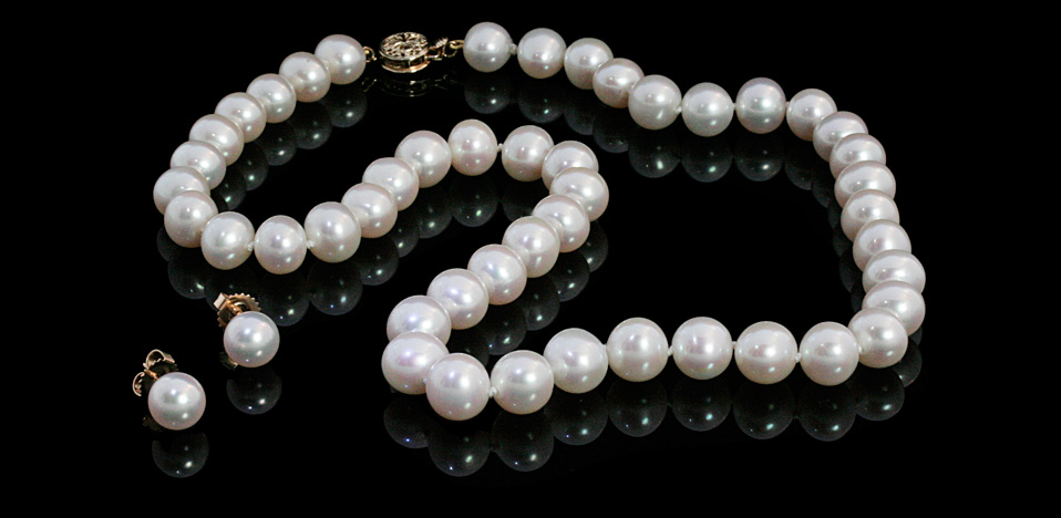 White pearl necklace and earrings on black background.