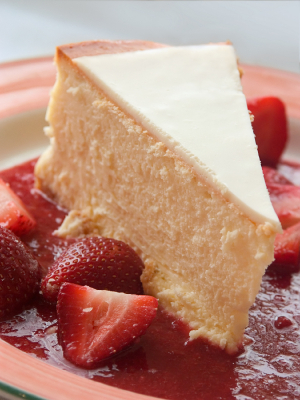 slice of cheesecake with strawberries on pink plate