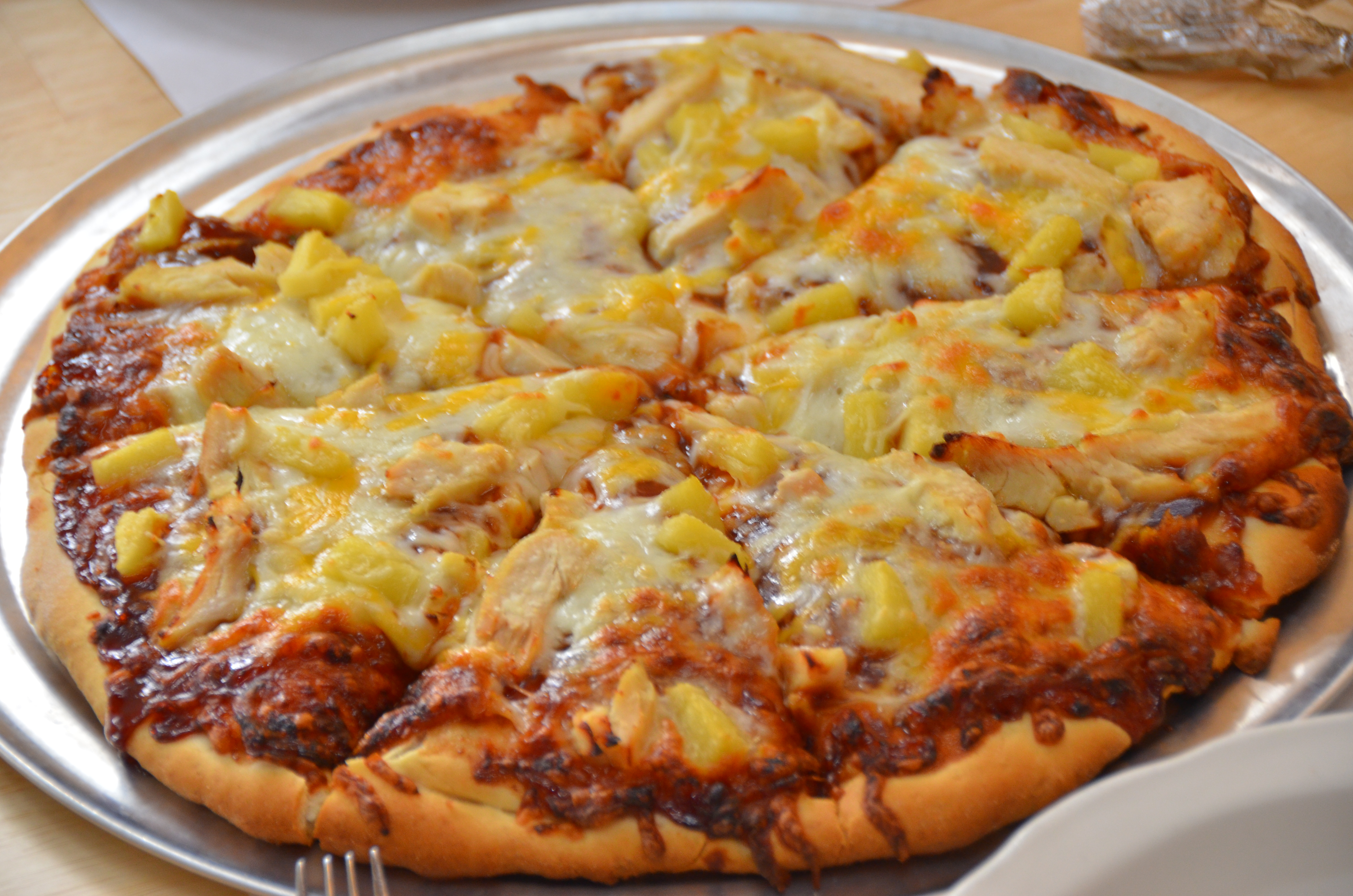 Whole pizza with chicken, pineapple, and cheese.