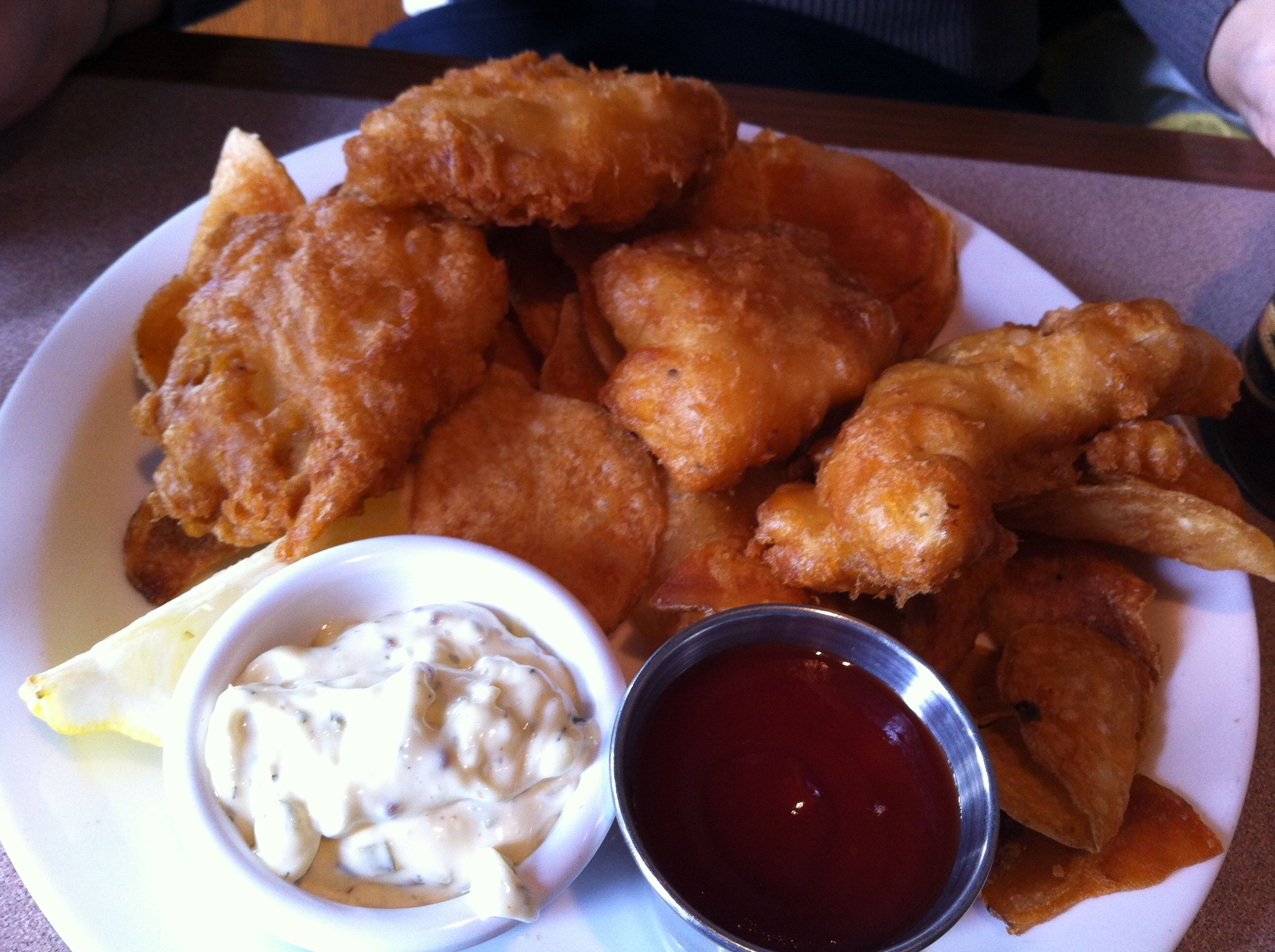 Fried fish and chips with tartar sauce and ketchup.