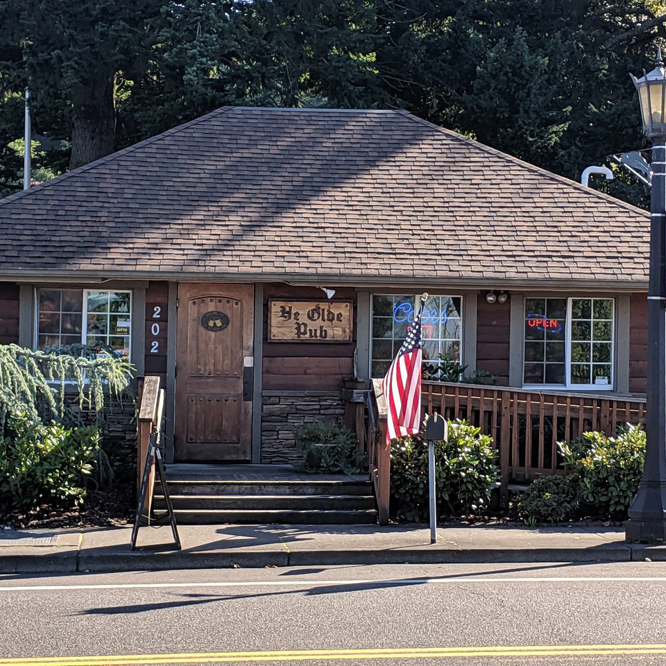 Street View of small pub with wood siding and front steps. ADA entrance ramp on the side near American flag.