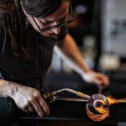 Woman uses heat torch on blown glass