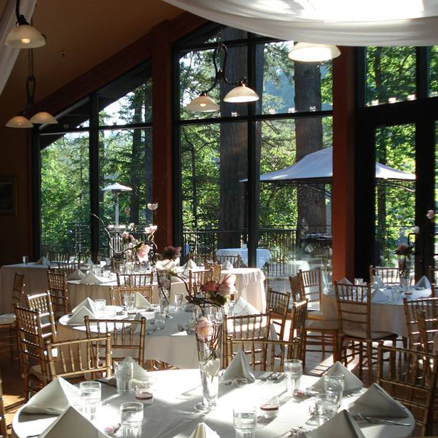 Elegant dining room with floor to ceiling windows featuring views of old evergreen trees.