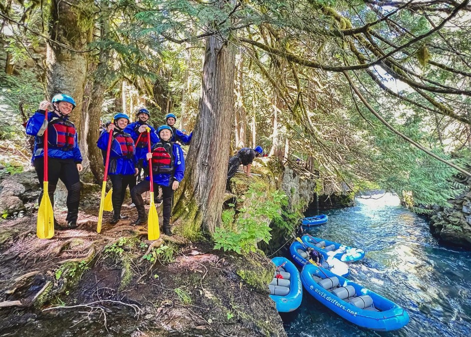 People Standing by tree with paddles and rafts in water
