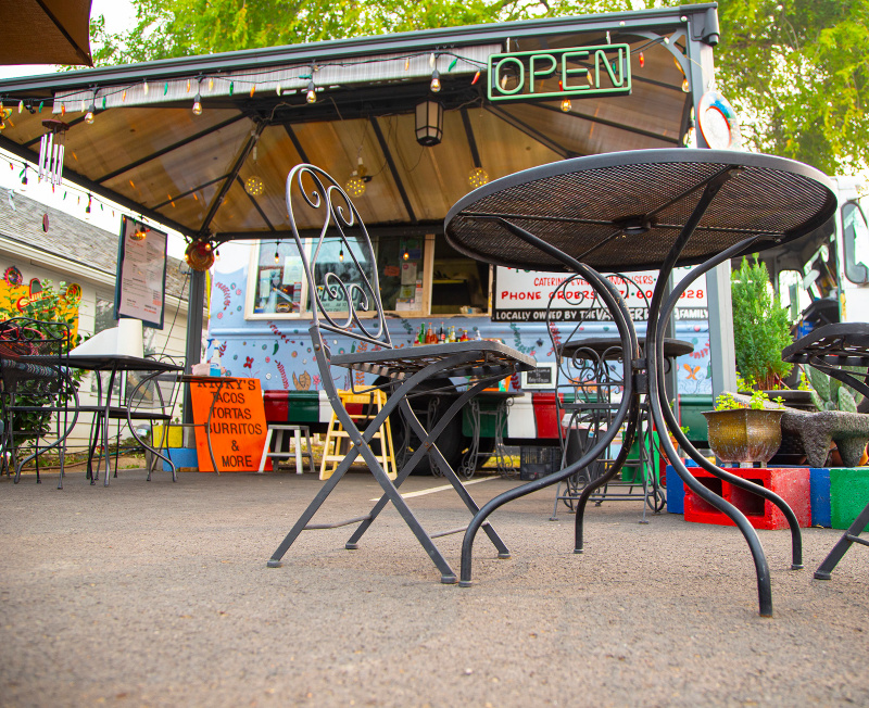 Table and chairs in front of Ricky's Tacos Food Cart