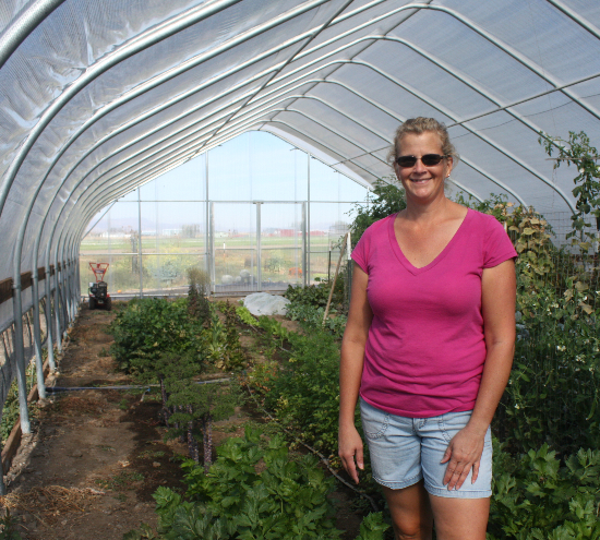 woman standing in greenhouse with pink shirt and jean shorts