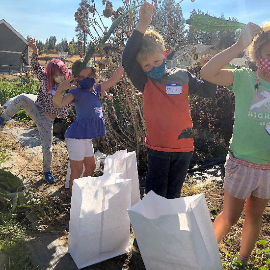 children shown with masks on in field harvesting crops and acting silly