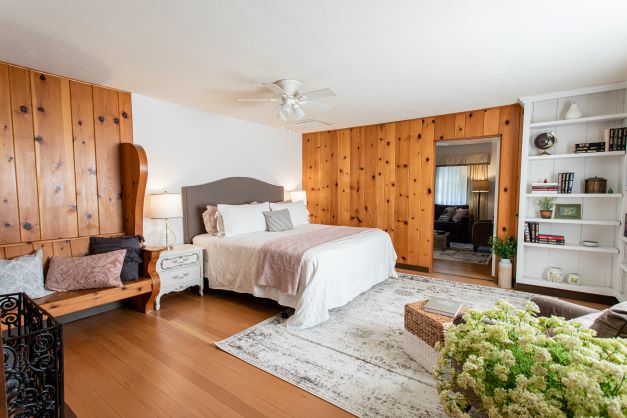 guest room with wood panelled walls, double bed, bench and shelf built in to wall