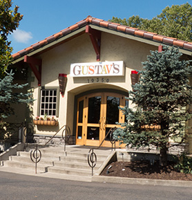 Gustav's entrance with a sign above, surrounded by trees.