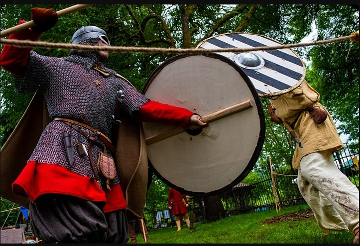 two people dressed as Vikings holding shields engaged in live action role play