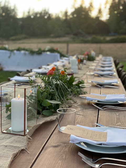 An outdoor table lined up with plates for dinner.