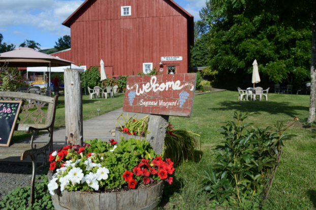 Welcome sign in front of a red barn at Saginaw Vineyard Cottage.