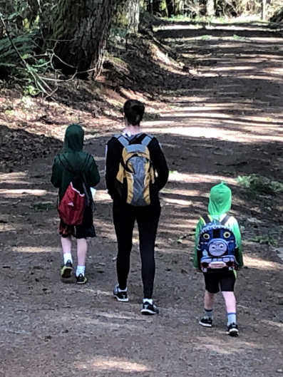 A mon and her two sons walking down a forest hiking path.