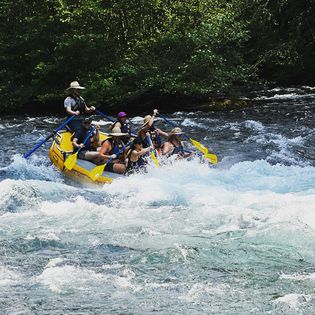A group of people rafting down rapids with a guide.