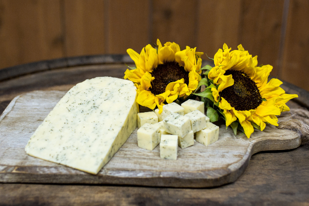 A block of cheese on a cutting board with sun flowers.