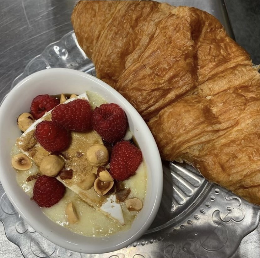 Cheese and fruit accompanied with a croissant.