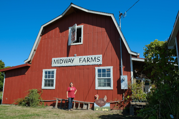 A person standing in front of a red barn.