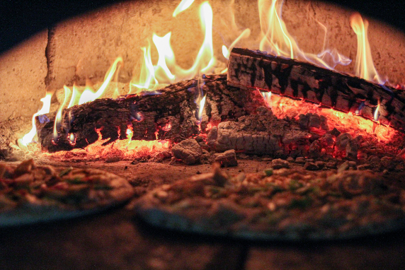Pizzas cooking in a wood fire brick oven.