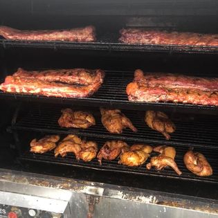 Ribs and chicken smoking in a smoker.