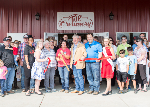 A large group of people gathered around for a ribbon cutting at TMK Creamery.