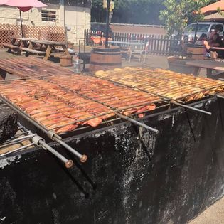 Meat being grilled over a charcoal pit.