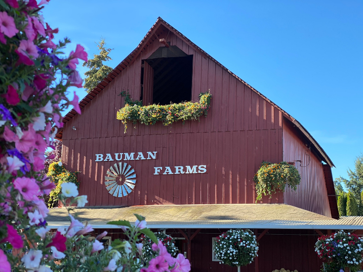 A red metal barn with flowers in front of it.