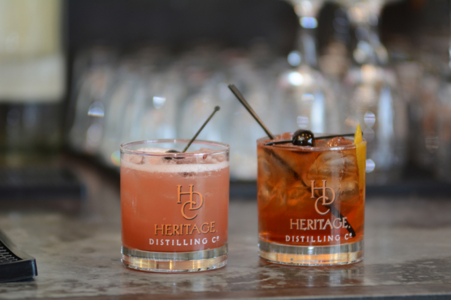 Two cocktails sitting on the bar counter from Heritage Distilling Company.