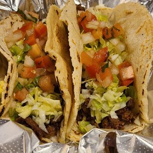 two tacos with meat, lettuce and pico de gallo