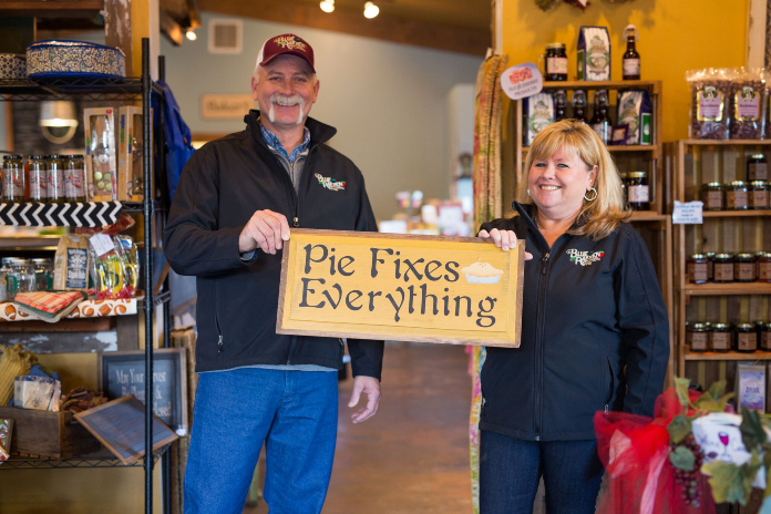Two people holding a sign saying pie fixes everything.