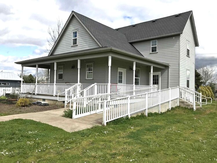 two story farmhouse with large porch and ramp