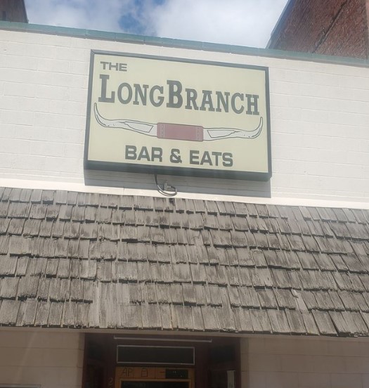 exterior of brick restaurant building with awning and sign for The LongBranch Bar & Eats